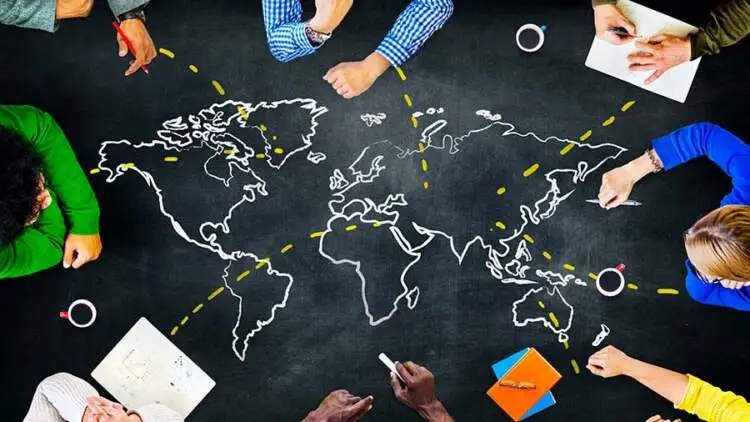 A team draws a world map and sourcing routes on a chalkboard during a planning session